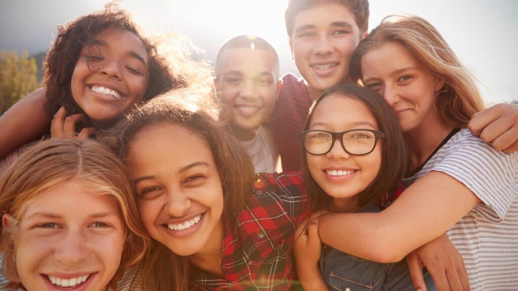 a smiling group of young people with sunlight glowing behind them