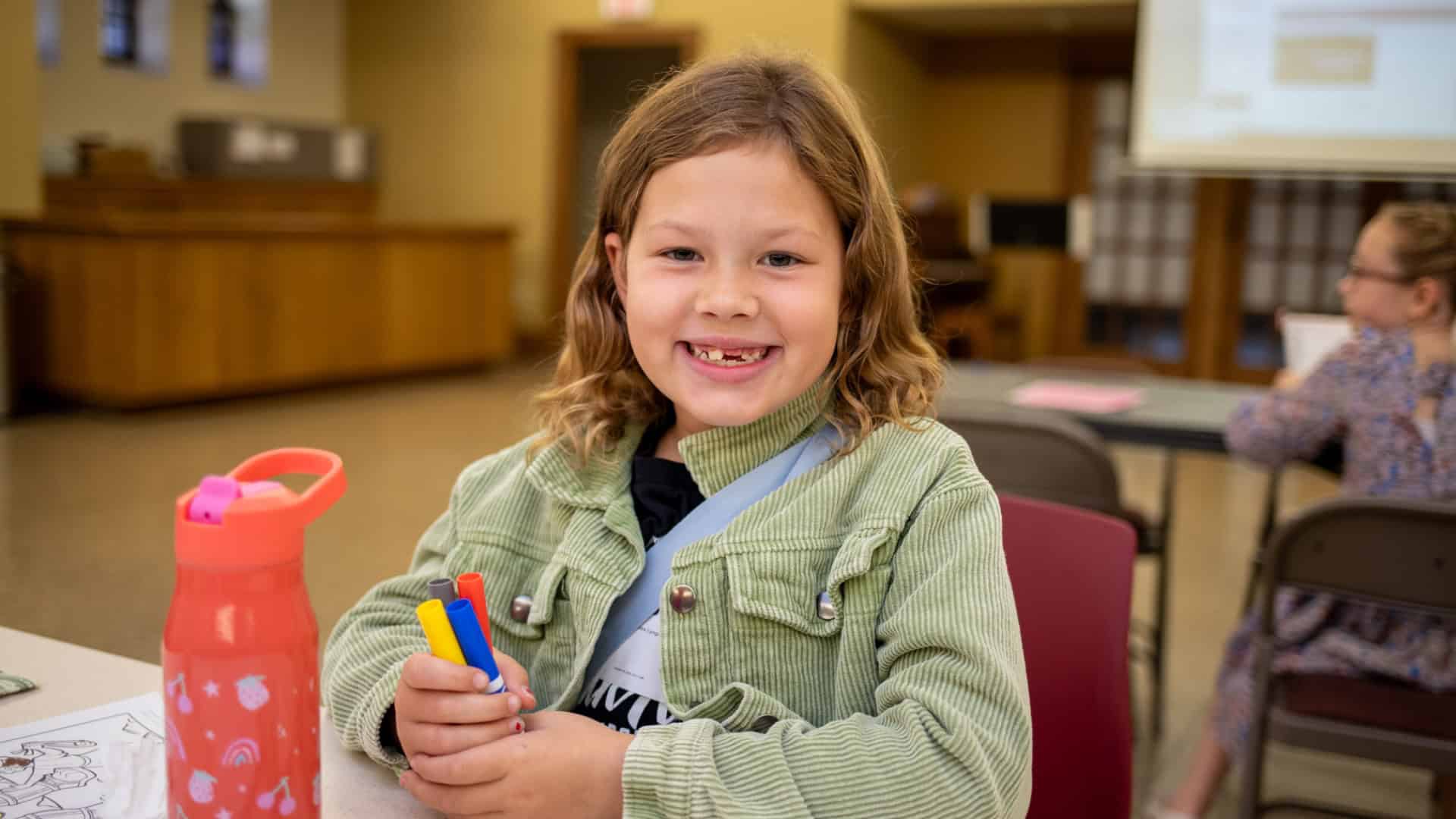 a smiling girl seated at a table