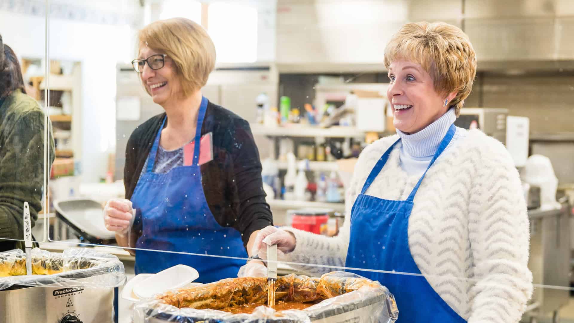 two happy women serving soup