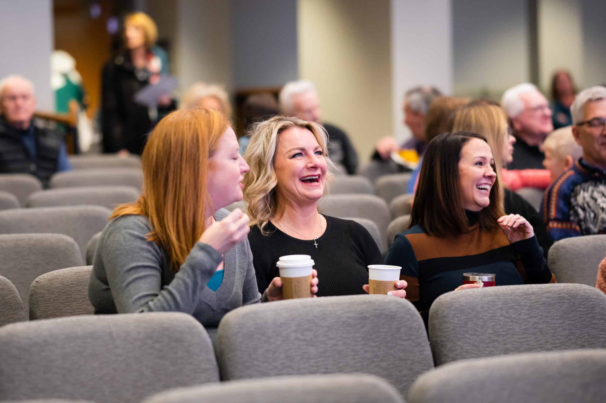 three happy women laughing while seated in the Celebration Center